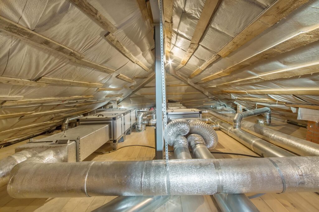 Technician installing attic insulation and checking roof vents