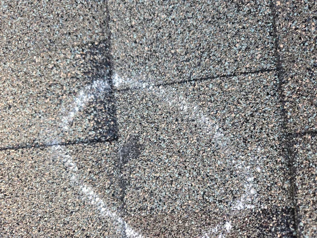 Close-up of a roofer replacing a few damaged shingles on an asphalt roof