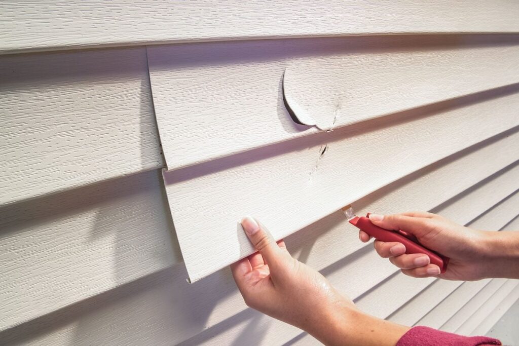 Siding Repair vs. Replacement: How to Know Which Option Is Right for You 1 Technician replacing a single damaged siding panel with matching material